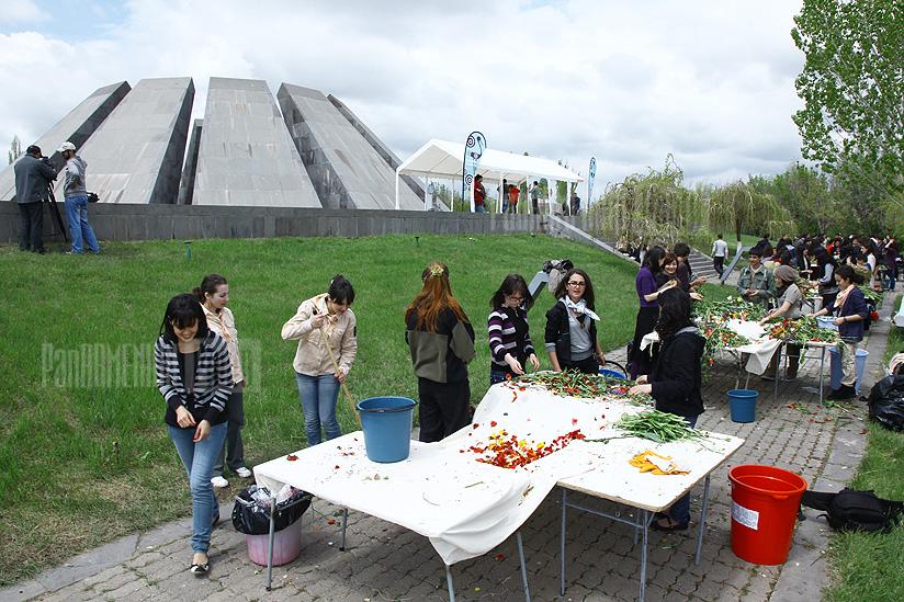 Волонтеры собирают цветы и венки, поднесенные к мемориальному комплексу Геноцида армян