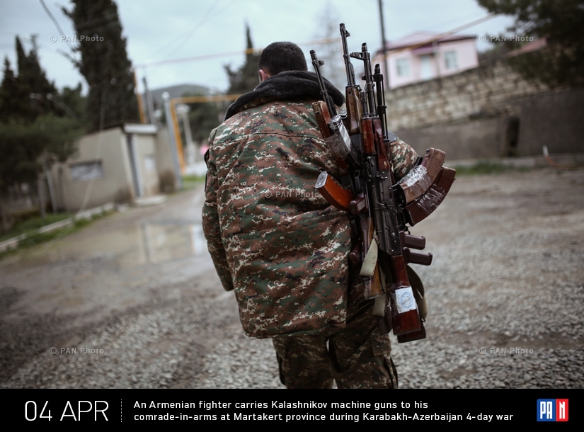 An Armenian fighter carries Kalashnikov machine guns to his comrade-in-arms at Martakert province during Karabakh-Azerbaijan 4-day war 