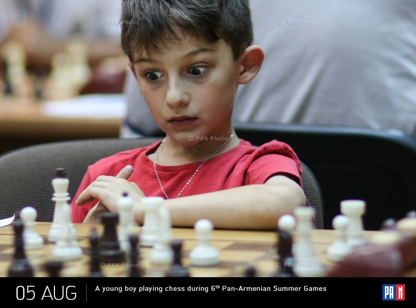 A young boy playing chess during 6th Pan-Armenian Summer Games